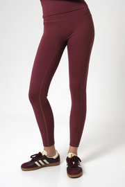 Burgundy leggings worn by a woman on a white background