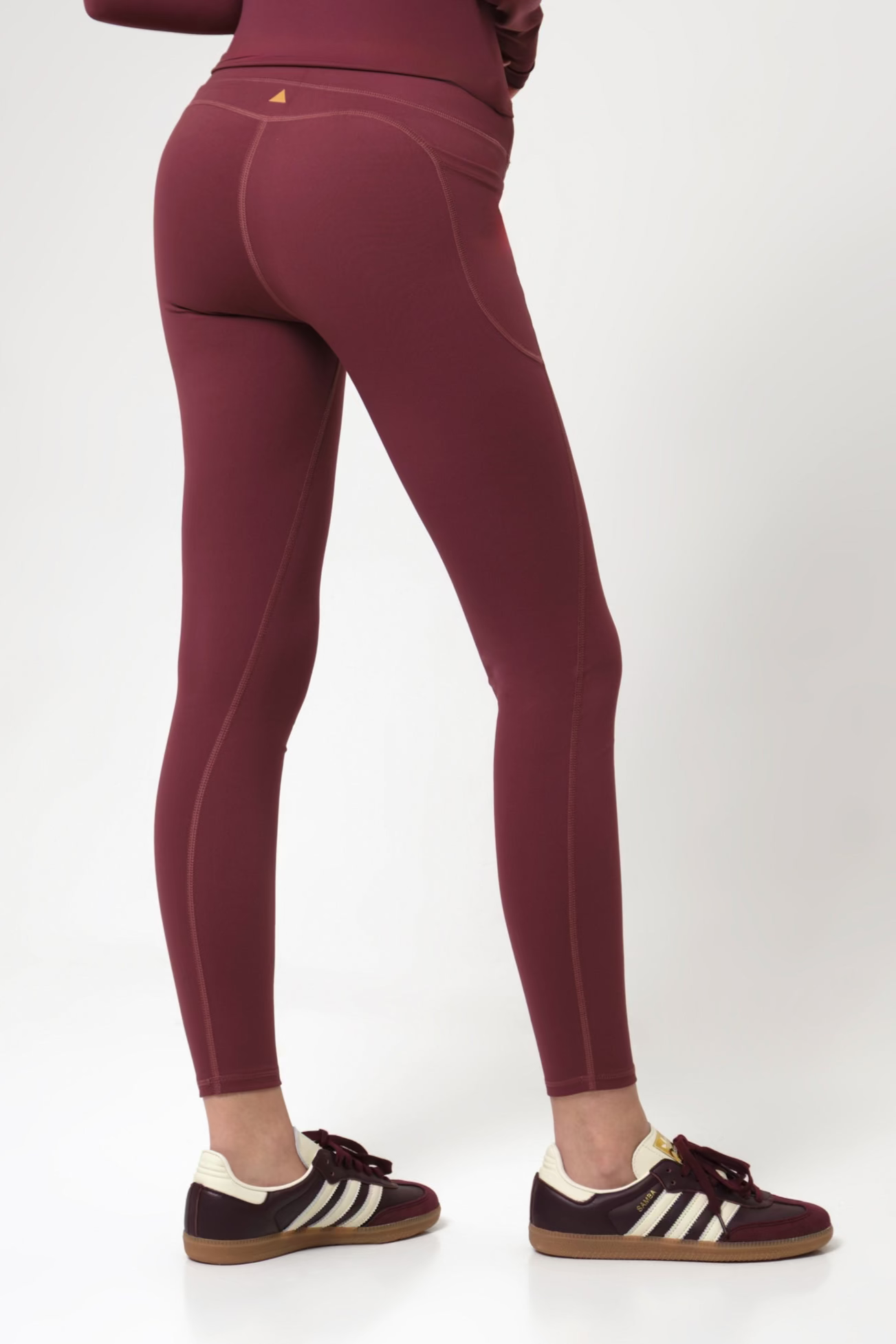 Burgundy leggings worn by a woman on a white background