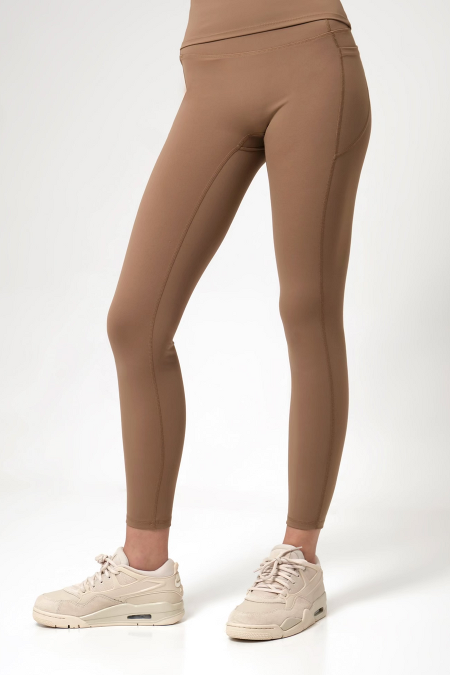 Brown leggings worn by a woman on a white background