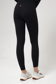 Woman wearing black leggings with a small logo on a white background