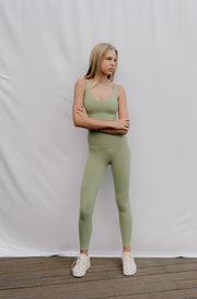 Woman wearing a green athletic outfit standing against a plain white background