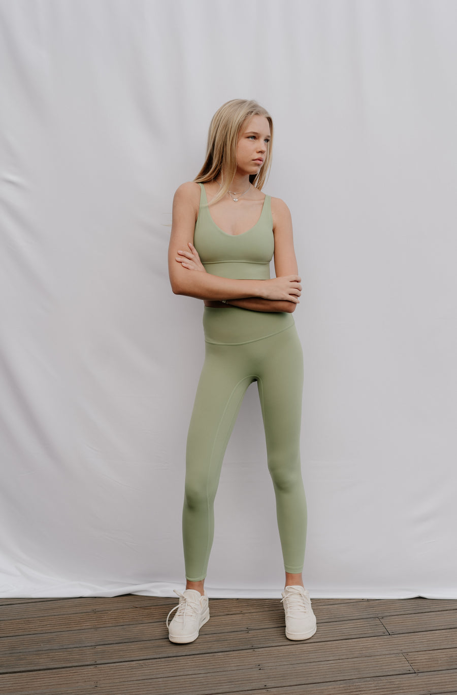 Woman wearing a green athletic outfit standing against a plain white background