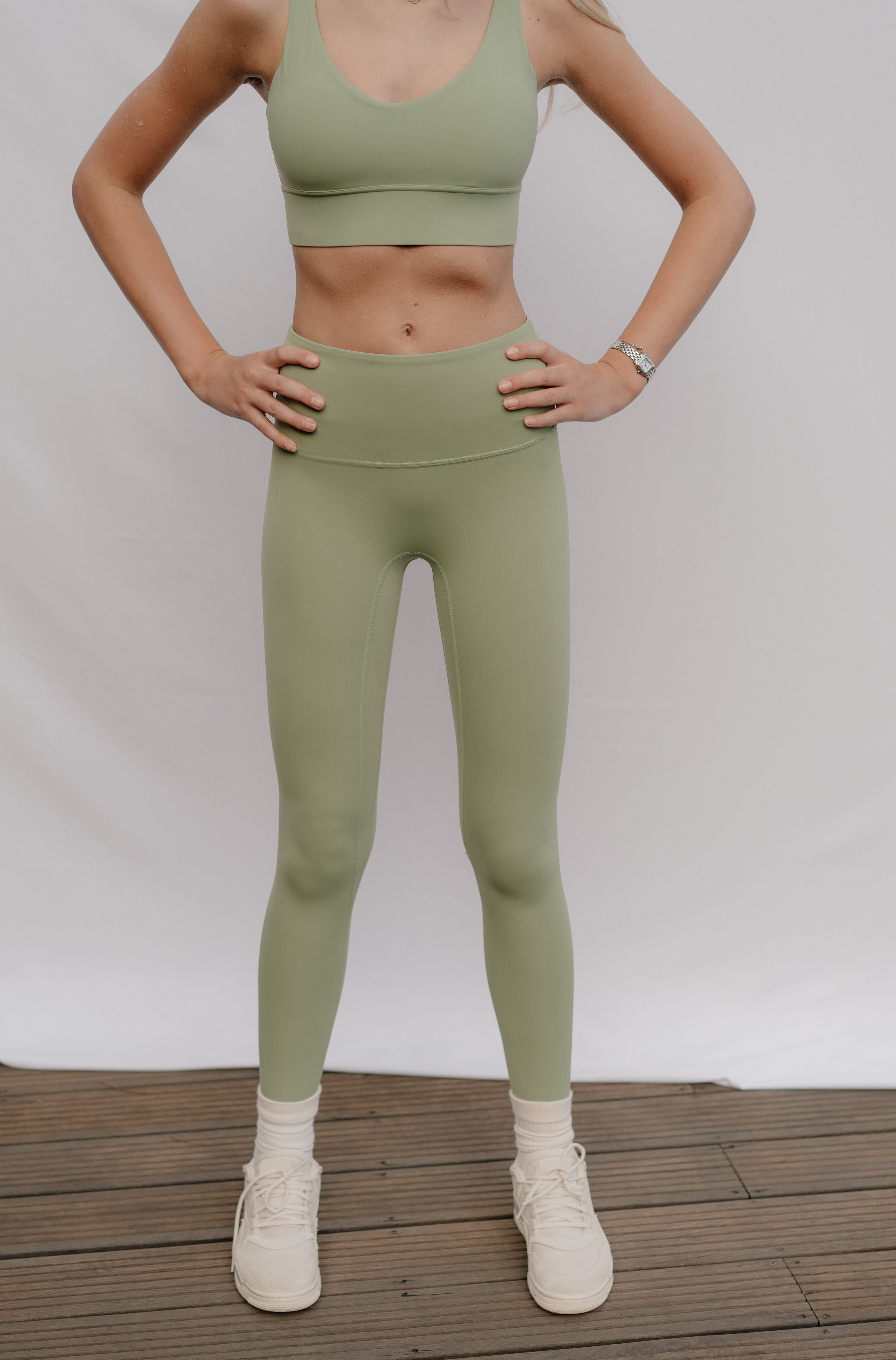 Woman wearing green athletic outfit on a white background