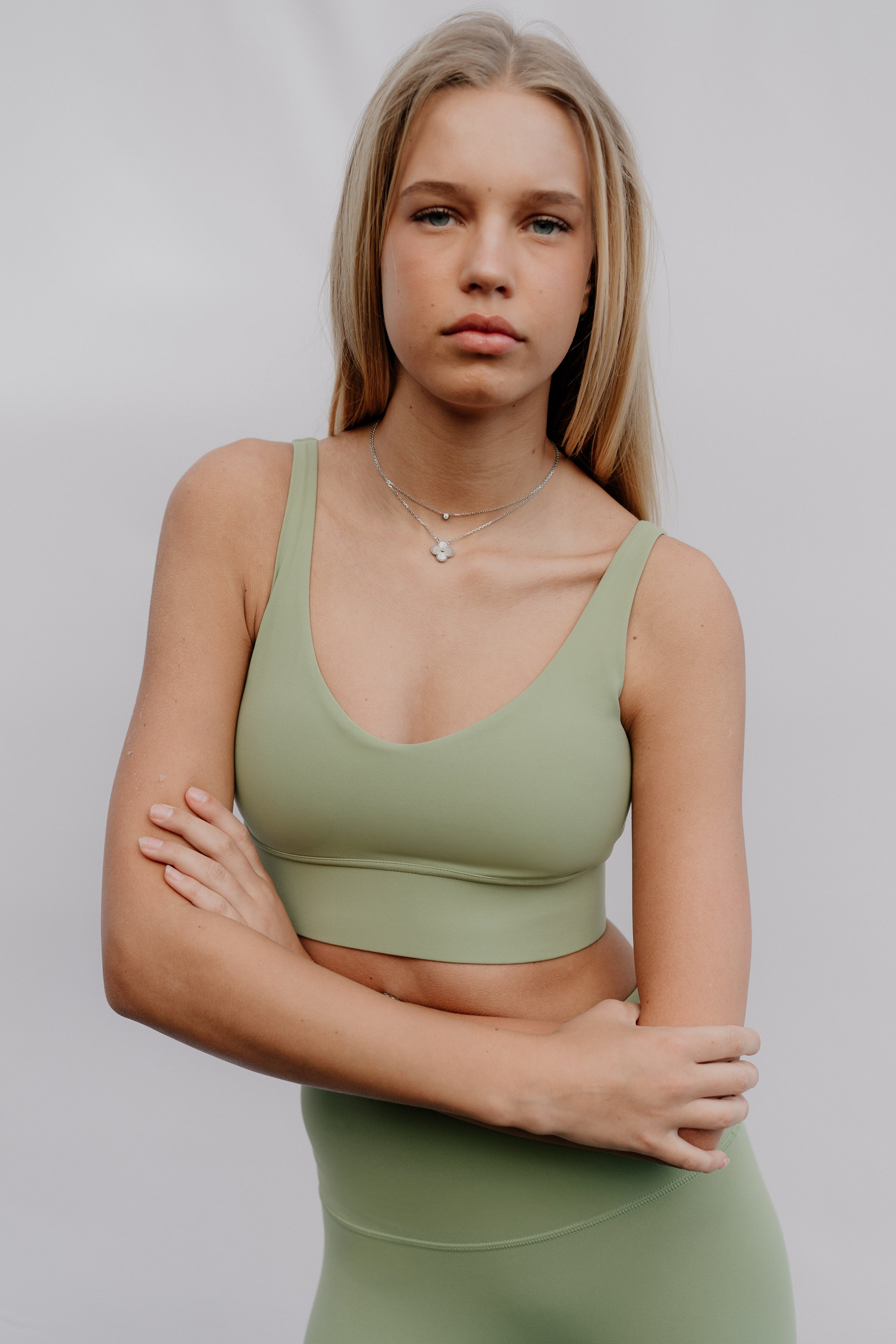 Woman wearing a green sports bra and leggings against a plain background