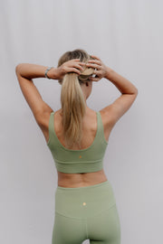 Person wearing a green sports bra and leggings against a plain background