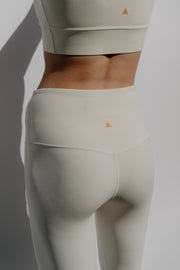 Ivory athletic leggings with a small triangle logo on a plain background