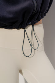 Close-up of a person wearing a navy jacket and beige pants with drawstrings.