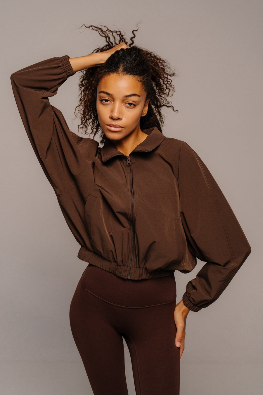Woman wearing a brown outfit against a plain background